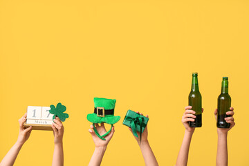 Female hands holding beer, cube calendar and party decor for St. Patrick's Day celebration on...