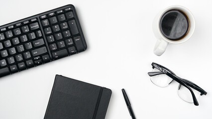 workspace desk with notebooks, pens, keyboard, glasses and coffee on white background