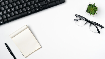 workspace desk with notebooks, pens, keyboard, glasses, plants on white background