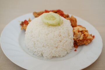 Rice with fried chicken and cucumber on white dish, stock photo