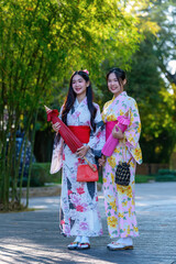 A young woman wearing a Japanese traditional kimono or yukata holding an umbrella is happy and...