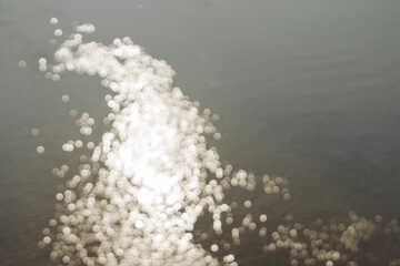 Blurred sparkling sunlight reflected on the water of a lake river