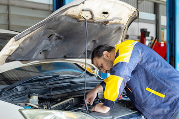 Indian repairman wearing uniform working in small business garage checking customer car maintenance or repair engine vehicle at workshop station, professional automotive business entrepreneur fix auto