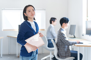 オフィスでパソコンを持つ私服の女性