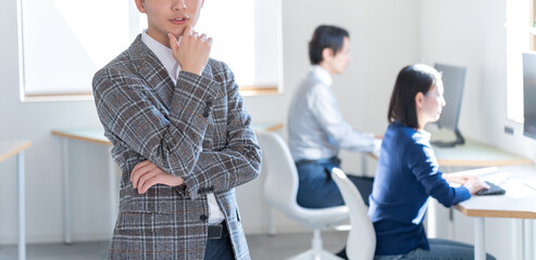 オフィスで考えるジャケットを着た若い日本人男性 - obrazy, fototapety, plakaty