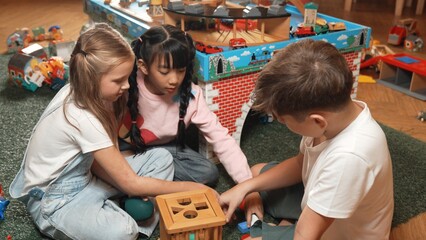 Top view of multicultural smart students playing wooden block together at playroom of kindergarten....