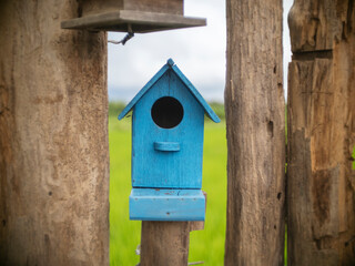 Old bird house or nest box hangs on the wooden fence.