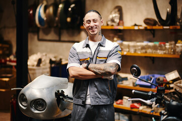Fototapeta premium Portrait of happy motorcycle mechanic standing in his workshop