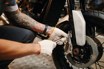 Mechanic in textile gloves changing motorcycle actuating lever