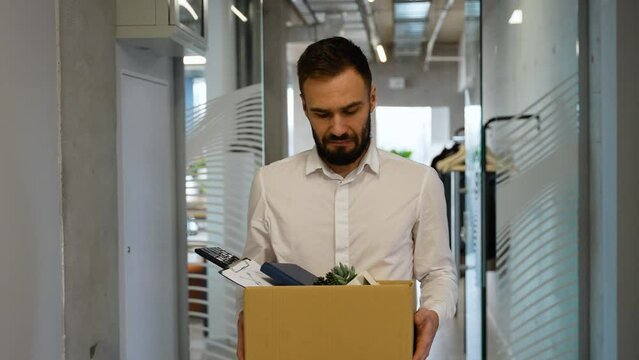 Dismissed worker leaving or resign or dismiss from job, man carry personal box walking out from office