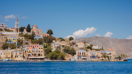 Symi Island, Greece. Greece islands holidays from Rhodos in Aegean Sea. Colorful neoclassical houses in bay of Symi. Holiday travel background. - obrazy, fototapety, plakaty