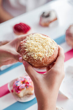 Hand holding blueberry with biscuit crumble topping doughnut in a cafe restaurant environment.