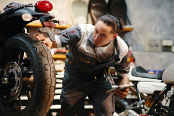 Fototapeta na wymiar Repairman checking wheels and tires of motorcycle in garage