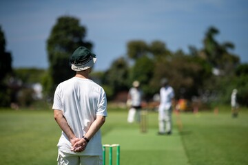 a local cricket match being played on a green cricket oval in summer in australia. australian...