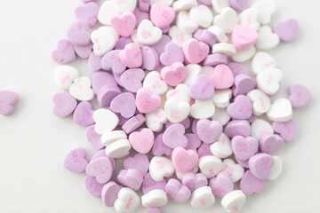 Background for Valentine's Day. Assorted pink, purple, white heart shaped candies with printed...