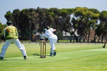 a local cricket match being played on a green cricket oval in summer in australia. australian...