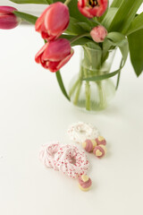 Pink tulips and heart-shaped pastries and candies on a white canvas close-up. Background for Valentine's Day, Easter. Gift for Women's Day, March 8th. Mockup