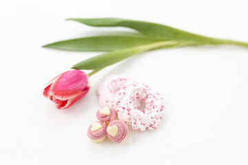 Pink tulips and heart-shaped pastries and candies on a white canvas close-up. Background for...