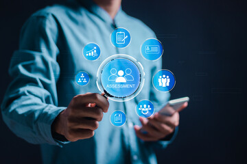 Assessment concept. Businessman use magnifying glass focus to assessment icons on  virtual screen for assessment analysis, evaluation measure and business analytics technology.