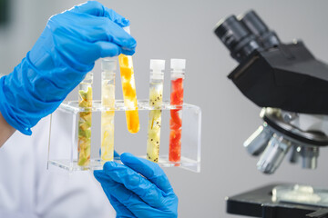 Scientist or researcher is holding a sample of fruit sample in test tube. Cosmetic laboratory. Experiment of vitamin in serum, skin care, lotion, healthy treatment, essence and medical body product.