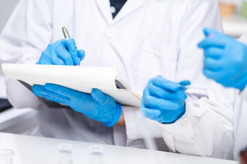 A Scientists or nutritionists are working on a sample of milk in biotechnology laboratory, genetic and bacteria research, dairy product quality control, protein, glucose and lactose percentage test.