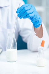 Close up of scientist or nutritionist measure temperature of milk, fat or glucose in a test tube or...