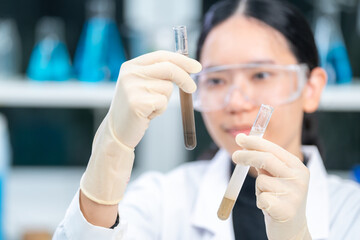 Expert female geologist or archaeologist holding a sample of soil in test tube, paleontology, archaeological and geological or mining laboratory. Concept of fossil research or soil experiment discover