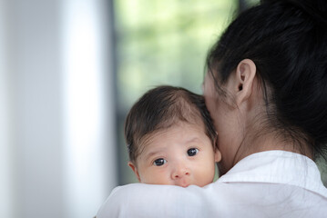 Close up of little adorable and cute new born baby or infant was holding by his or her Asian mother, mother embrace cuddle her child with softness and tender. Motherhood childcare love comfort concept
