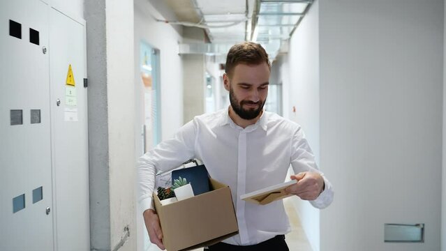 Sad Fired Young Employee Worker With Box Goes Along The Corridor