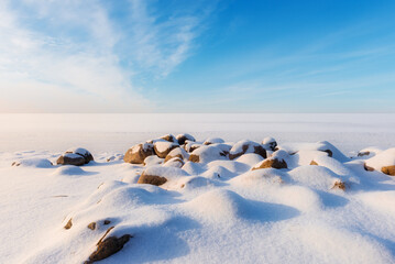 Beautiful winter landscape with stones on foreground and frozen lake - 716258384
