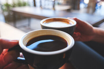 Closeup image of a couple people clinking coffee mugs in cafe