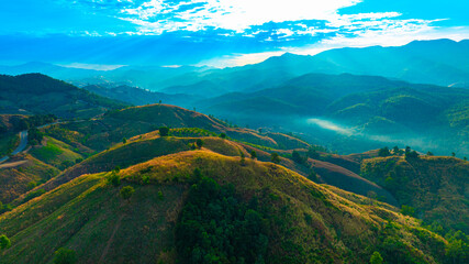 Aerial view of mountains and mixed forest. Green deciduous trees with mist clouds. The rich natural ecosystem of the rainforest concept is about conservation and natural reforestation.	