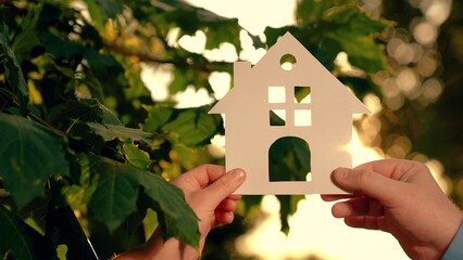 Concept building house family, child. Dream buy house. Paper house hands family, sun shines in window close-up. Hands, paper house at sunset. Symbol home, family comfort, happy. Real estate insurance