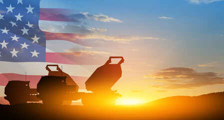 Artillery rocket system are aimed to the sky at sunset with USA flag. Multiple launch rocket...
