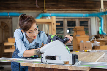 Young woman is training to be a carpenter in workshop. Carpenter working with equipment on wooden table. woman works in a carpentry shop.