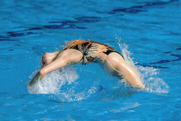 Essence of fluidity and grace, witness a synchronized swimmer's captivating dance in the mesmerizing embrace of the pool