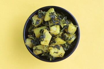 Aloo Palak sabzi, Spinach Potatoes dry curry served in a black bowl, Indian food