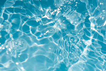 Bluewater waves on the surface ripples blurred. Defocus blurred transparent blue colored clear calm water surface texture with splash and bubbles. Water waves with shining pattern texture background.