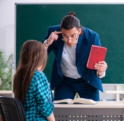 Young handsome teacher and female student in the classroom