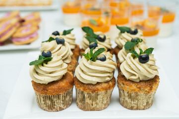 Cupcakes with cheese cream in a candy bar decorated with blueberries and mint