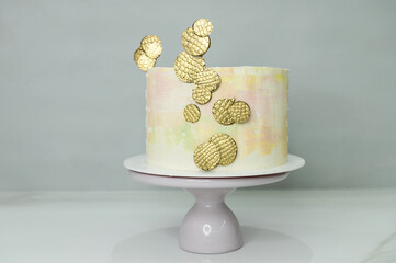 Bright colorful cake on a stand with chocolate centerpieces covered with gold paint