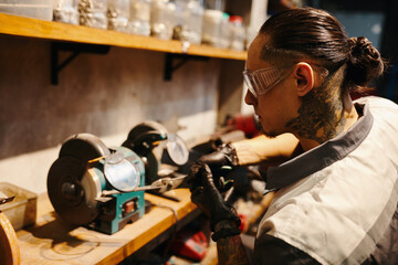 Mechanic in protective googles working at workbench in his garage