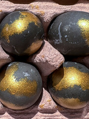 Black and gold eggs, colored like dragon eggs, are in the tray. The idea for coloring eggs for the Easter holiday. Close-up