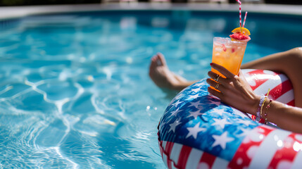 a woman relaxing in a swimming pool, sitting in an inflatable donut float patterned with the USA flag, holding a colorful cocktail