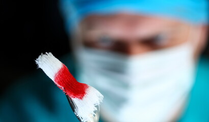 Surgeon in sterile uniform arms holding and passing to colleague tools with bio material wad...