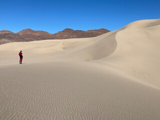 Lone hiker on sand dunes in desert