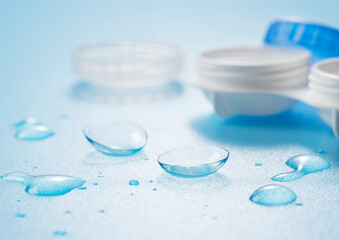 Contact lenses and cases placed on a blue background with water droplets. Image of contact lenses.