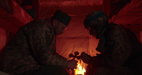 Confession of a Ukrainian soldier in a dark dugout. The chaplain and the warden sit opposite each other and talk.