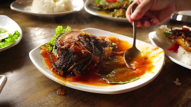 Homemade sweet and sour carp Gourami fish or Osphronemus goramy served on a white plate. Indonesian food called Ikan Asam Manis  