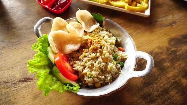 Asian fried rice called Nasi Goreng Kampung served with tomato slice, vegetables and crackers. Healthy asian food. 